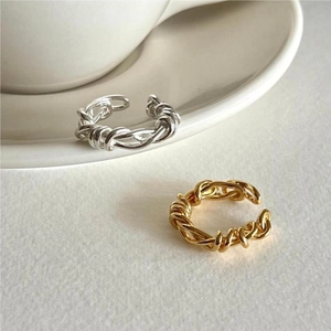 Detail of twisted rope design rings in gold and silver finish on white ceramic saucer