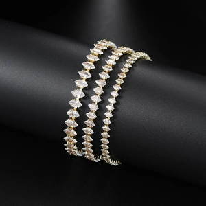 Detailed view of three gold tennis bracelets with marquise zircon stones on black display