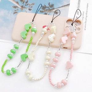 Detailed view of handmade beaded phone lanyards in green, beige and pink with resin hearts