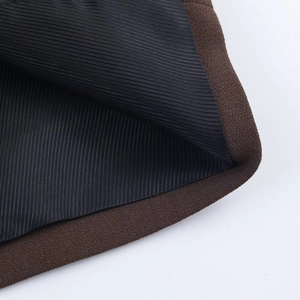 Close-up of the blazer cuff showing dark brown outer fabric and black lining texture