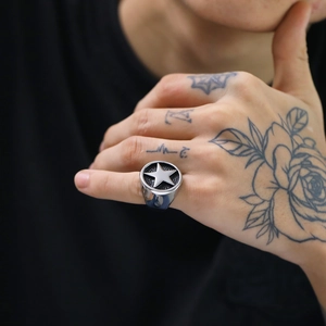Close-up of men's silver star signet ring in punk style worn by a tattooed model