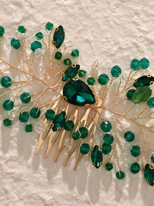 Macro shot of handcrafted gold wire comb with emerald green crystals and beadwork detail