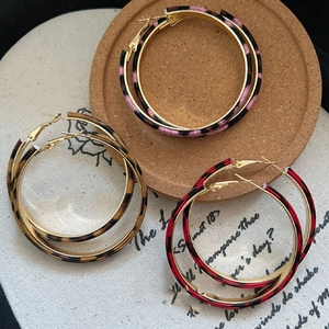 Close-up of leopard print hoop earrings in pink brown and red colors with gold finish