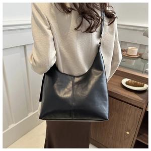 Detailed view of the large black leather tote bag worn as a shoulder bag on a model