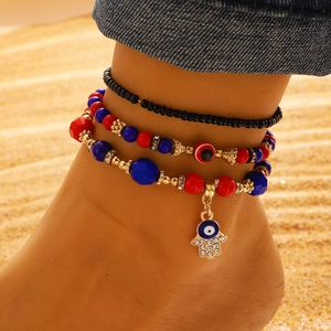 Set de tobilleras bohemias con ojo turco y mano de Fátima sobre fondo de playa de arena