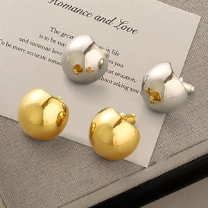 Close-up of minimalist gold and silver bean-shaped earrings on a stylish card