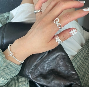Detailed view of twisted silver rings and link bracelet styled with casual apparel