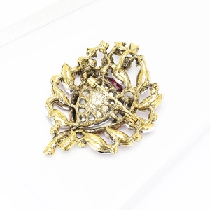 Detail view of the vintage gold brooch back with red gemstones and safety pin clasp