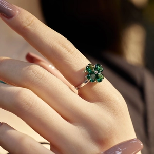 Detail shot of a silver ring featuring a green zircon four-leaf clover on a model finger