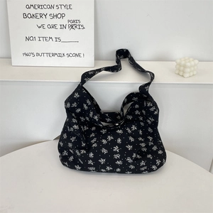 Gros plan détaillé d'un sac en toile noire à fleurs avec motifs blancs et décor épuré