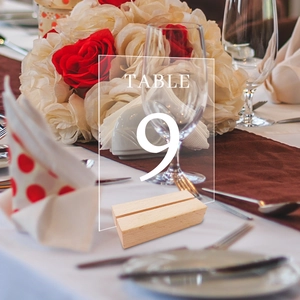 Close-up of Table 9 acrylic sign with rustic wooden base set in a wedding floral scene