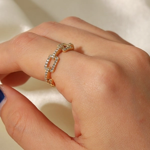 Detail of 18K gold plated chain ring with zircon pave on model's finger with silk background