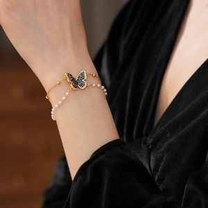 Close-up of a double-layer gold butterfly bracelet with pearls and pavé set zircons