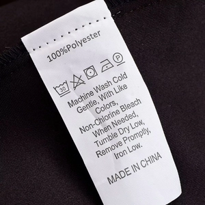 Gros plan de l'étiquette d'entretien 100% polyester avec icônes de lavage sur tissu noir