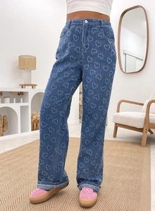 Close-up of washed blue denim jeans featuring white heart crochet pattern and texture