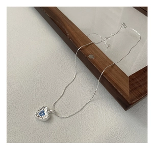 Detail of silver heart necklace with blue gemstone and irregular hammered texture