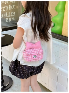 Close-up of girl's pink tweed crossbody bag featuring a bow and silver metal chain strap