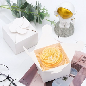 Detail of white petal-top cardstock gift box shown open with a candle inside