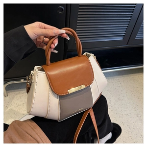 Detail view of the brown and beige color-block faux leather handbag with gold hardware