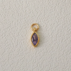 Detailed close-up of a gold-plated necklace pendant with a purple marquise zircon stone