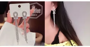 Detail of silver long tassel earrings with bow design and crystals on a female model
