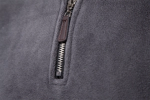 Detailed macro view of metal half-zipper with brown leather pull on grey fleece sweater