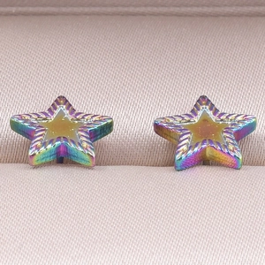 Macro detail of star-shaped earrings with rainbow electroplating and radial engravings