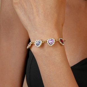 Gros plan du bracelet doré avec pierres précieuses multicolores en forme de cœur