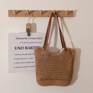 Hollow out cotton woven shoulder bag with brown leather straps hanging on a wall