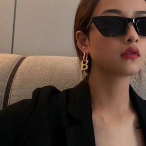 Golden B letter drop earrings for women shown on a model with stylish indoor lighting