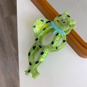 Detail einer grünen Frosch-Haarklammer aus Acetat mit schwarzen Punkten und Kristallaugen