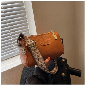 Detail der Crossbody-Tasche mit Lychee-Struktur und breitem Ethno-Webgurt