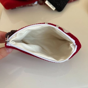 Macro detail of red knitted coin purse showing white fabric lining and zipper closure