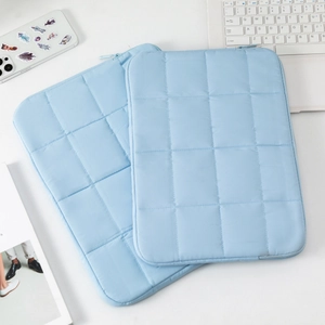 Close-up of light blue quilted laptop sleeve with grid stitching and smooth zipper