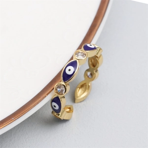 Macro detail of gold evil eye ring with blue enamel and pavé zircon on white porcelain