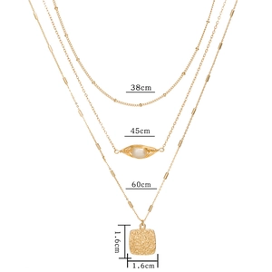 Detailed view of triple-layered gold chain necklace with pearl and square hammer pendant