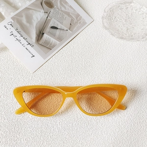 Flat lay of cat-eye sunglasses with yellow frames and orange lenses on textured fabric