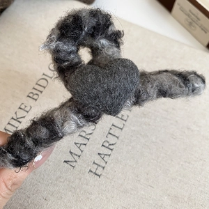 Détail de la pince à cheveux grise en forme de cœur avec une élégante texture en peluche