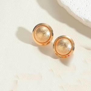 Detail shot showing dual-texture gold round stud earrings with matte and polished finish