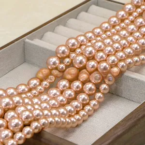 Macro view of metallic rose gold pearls in various sizes on a grey jewelry tray