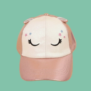 Detail of kids baseball cap showing rose gold metallic leather and glitter fabric with unicorn embroidery
