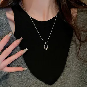 Minimalist silver stainless steel snake chain necklace with oval geometric pendant worn by model