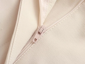 Close-up of seamless color-matched zipper on elegant beige slim-fit trouser fabric