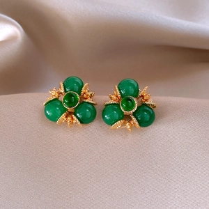 Détail des boucles d'oreilles vintage avec perles vertes sur soie couleur champagne