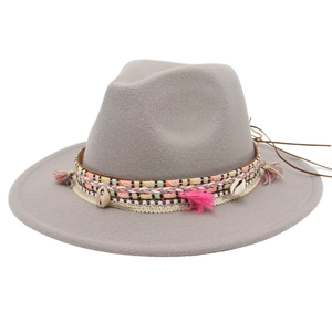 Detail of gray wool fedora hat featuring bohemian tassel band and natural shell accents