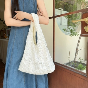 Détail d'un sac à main en dentelle crochetée blanche avec des motifs floraux délicats