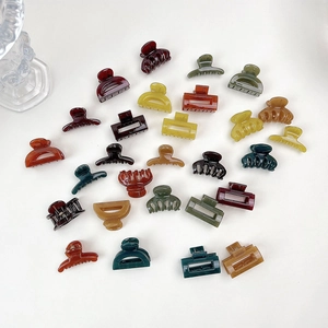 Flat lay of small jelly hair clips in assorted shapes and retro colors on white background