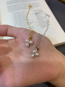 Close-up of pearl zircon flower pendant necklace held in hand over a vintage book