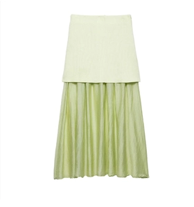 Détail montrant le tricot vert clair et la texture plissée en soie de la jupe longue
