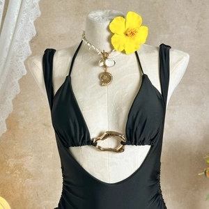 Detail of sexy black halter swimsuit featuring a centered gold metal ring and cut-outs